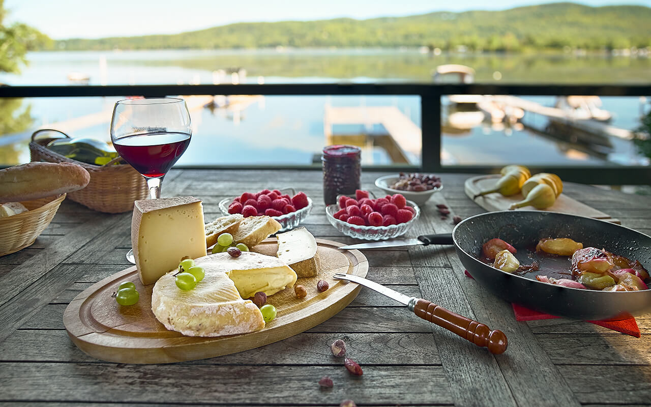 Assortment of cheese on a wooden tray with wine, on the table, house terrace the lake, by day, there are no people