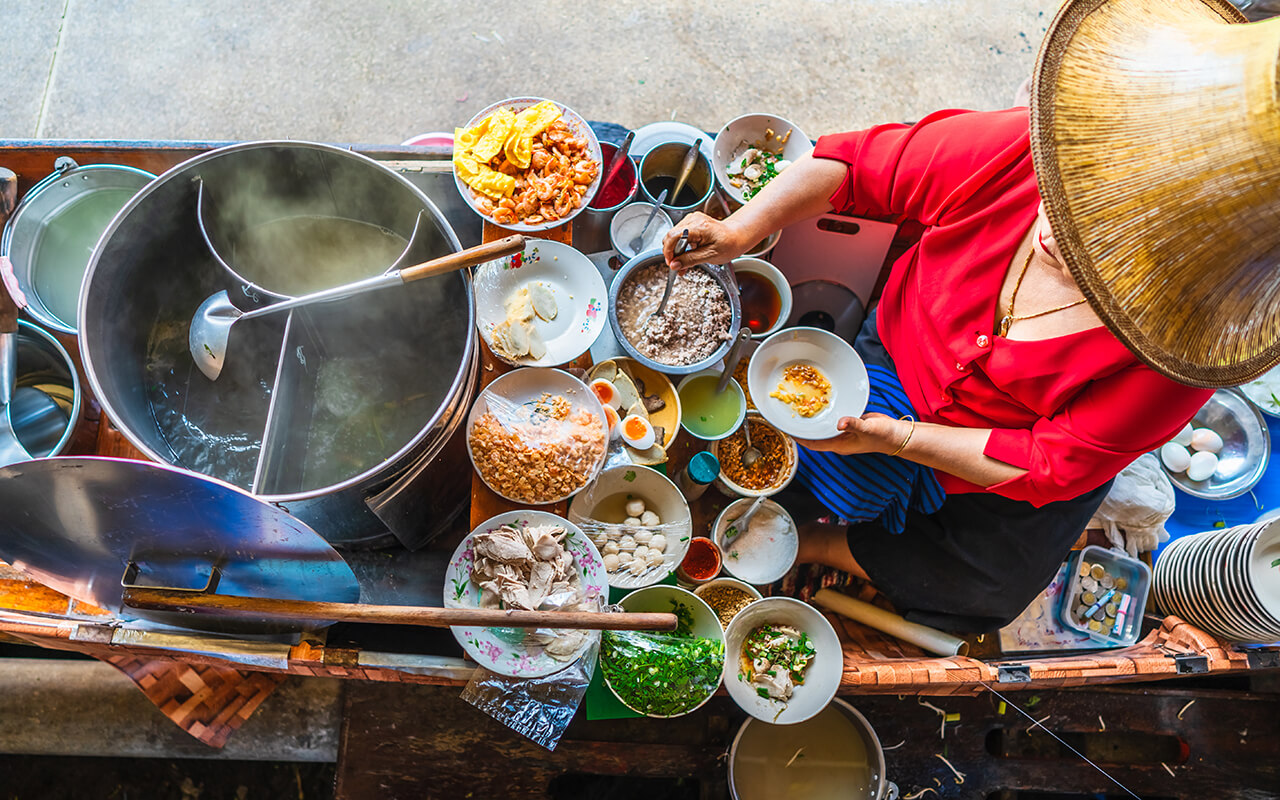 Top view old woman cooking Thai noodle soup Tom Yam style on Thai tradition boat in local floating market