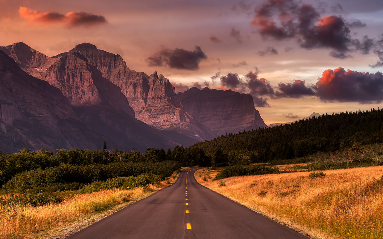 Beautiful View of Scenic Highway with American Rocky Mountain Landscape in the background. Colorful Summer Sunrise Sky. Taken in St Mary, Montana, United States.