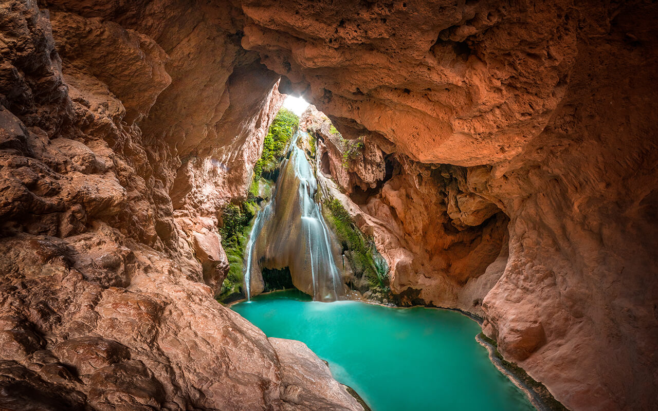 A beautiful waterfall inside a cave and a lake of crystal clear turquoise water. 