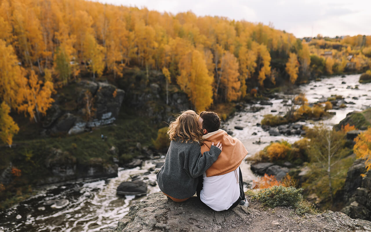 A happy couple in love in casual clothes travel together, hike and have fun in the autumn forest, enjoy nature on a weekend in fall.