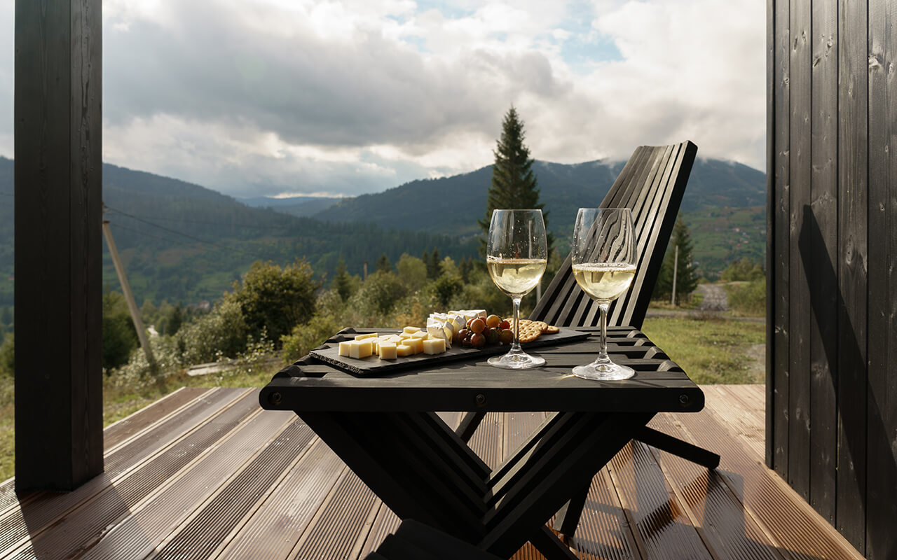 White wine glasses and plate of cheese on terrace with mountains view