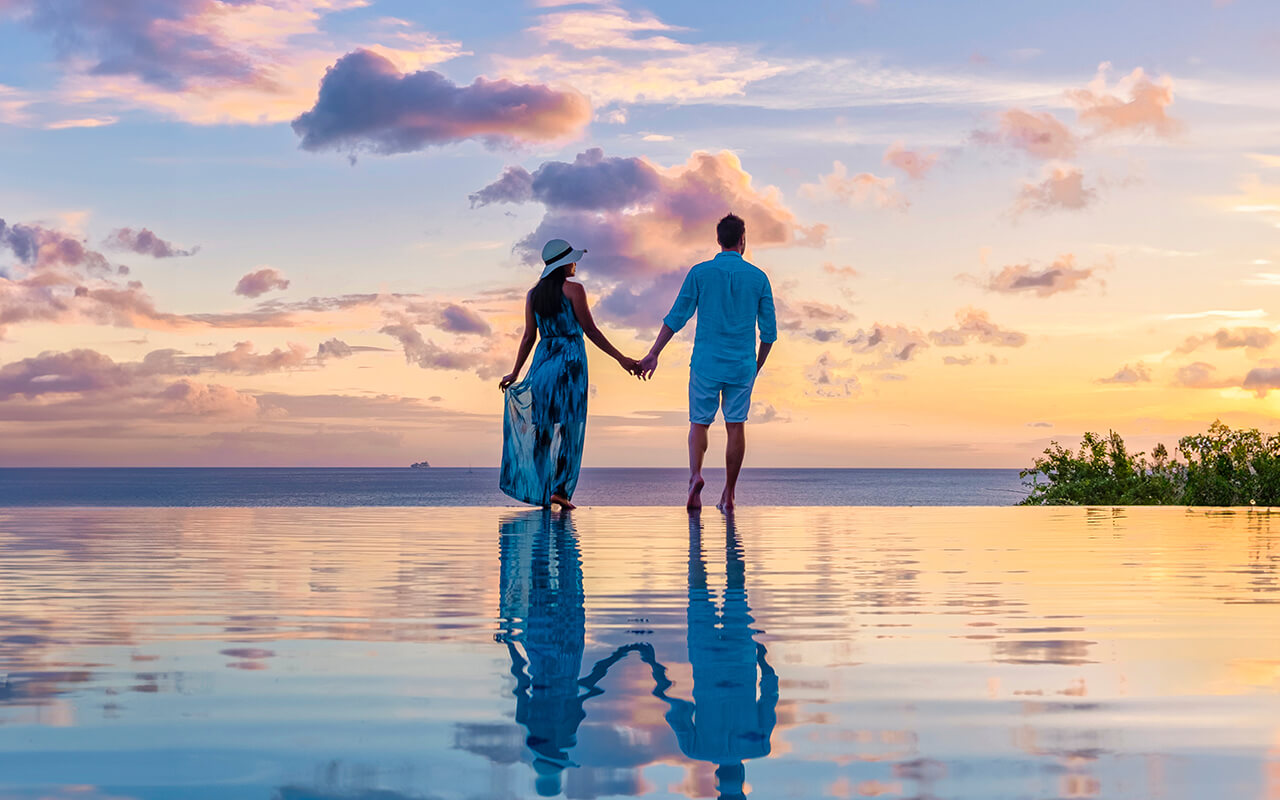 Young men and women watching the sunset with reflection in the infinity swimming pool at Saint Lucia Caribbean