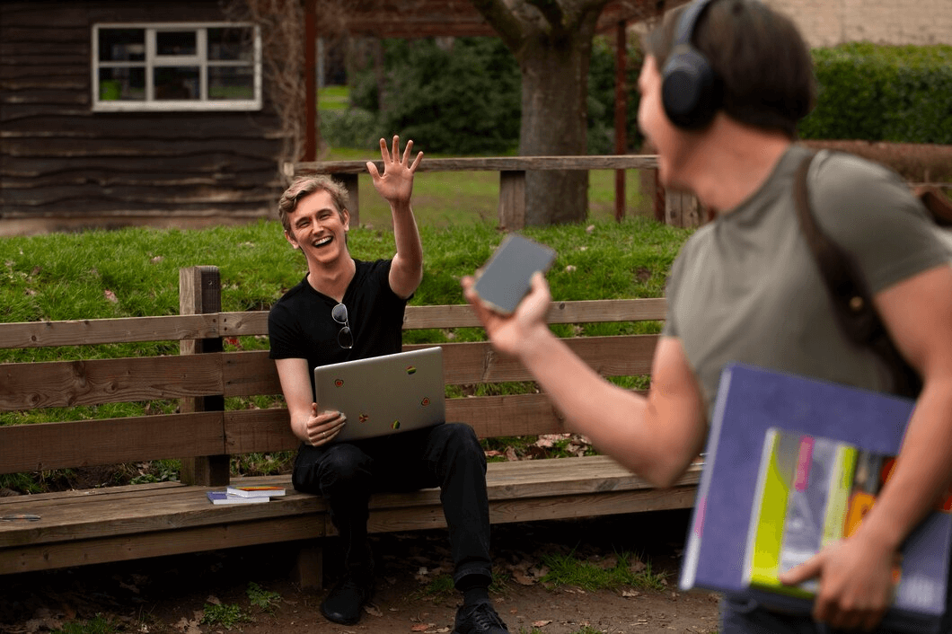Friends waving to each other in a park