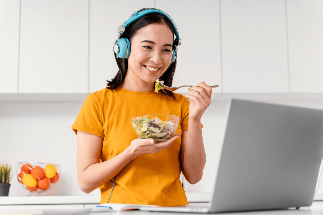 woman eating salad with headphones on 