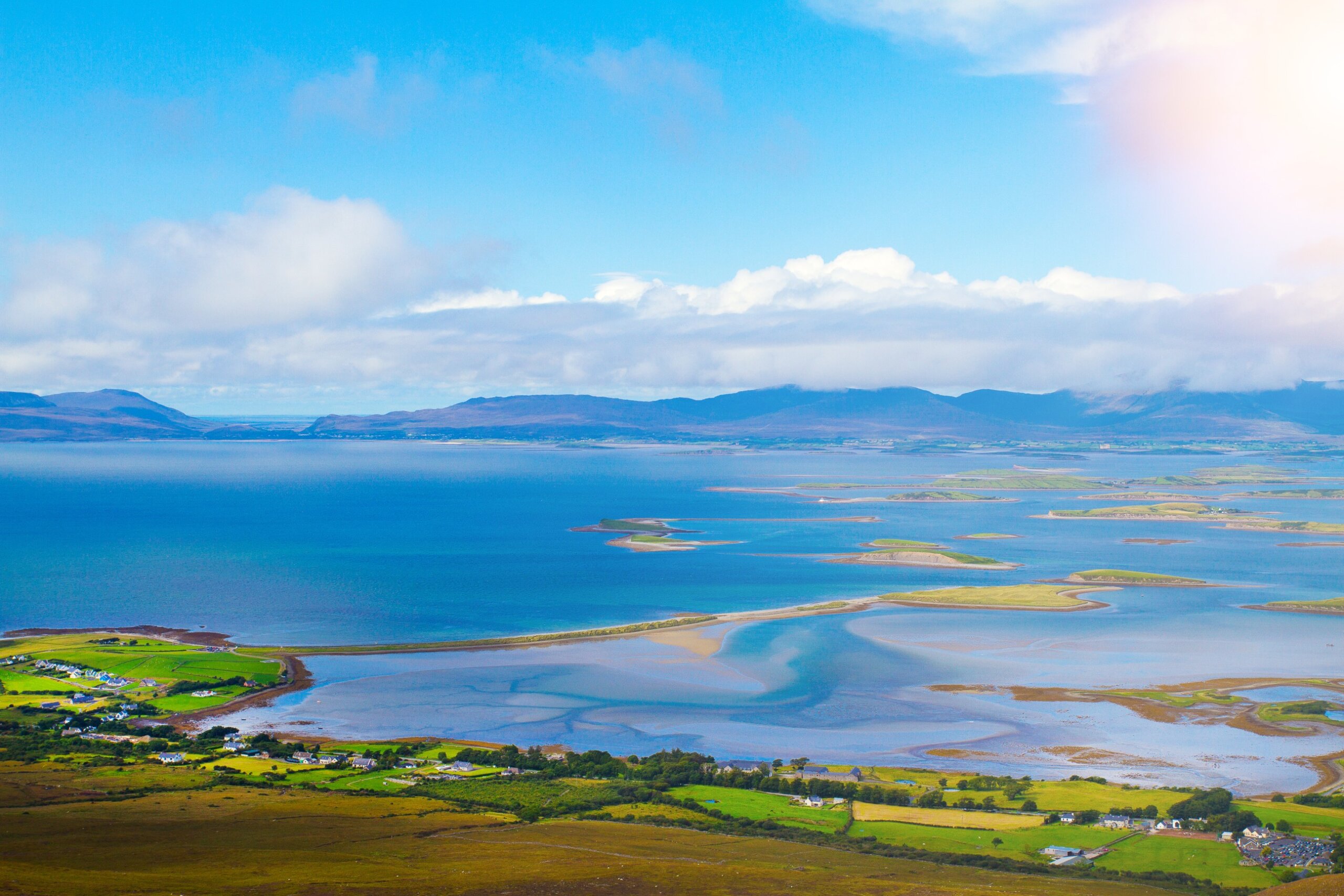 Panoramic coastal landscape in Ireland with green fields and blue water, St. Patrick’s Day travel destinations