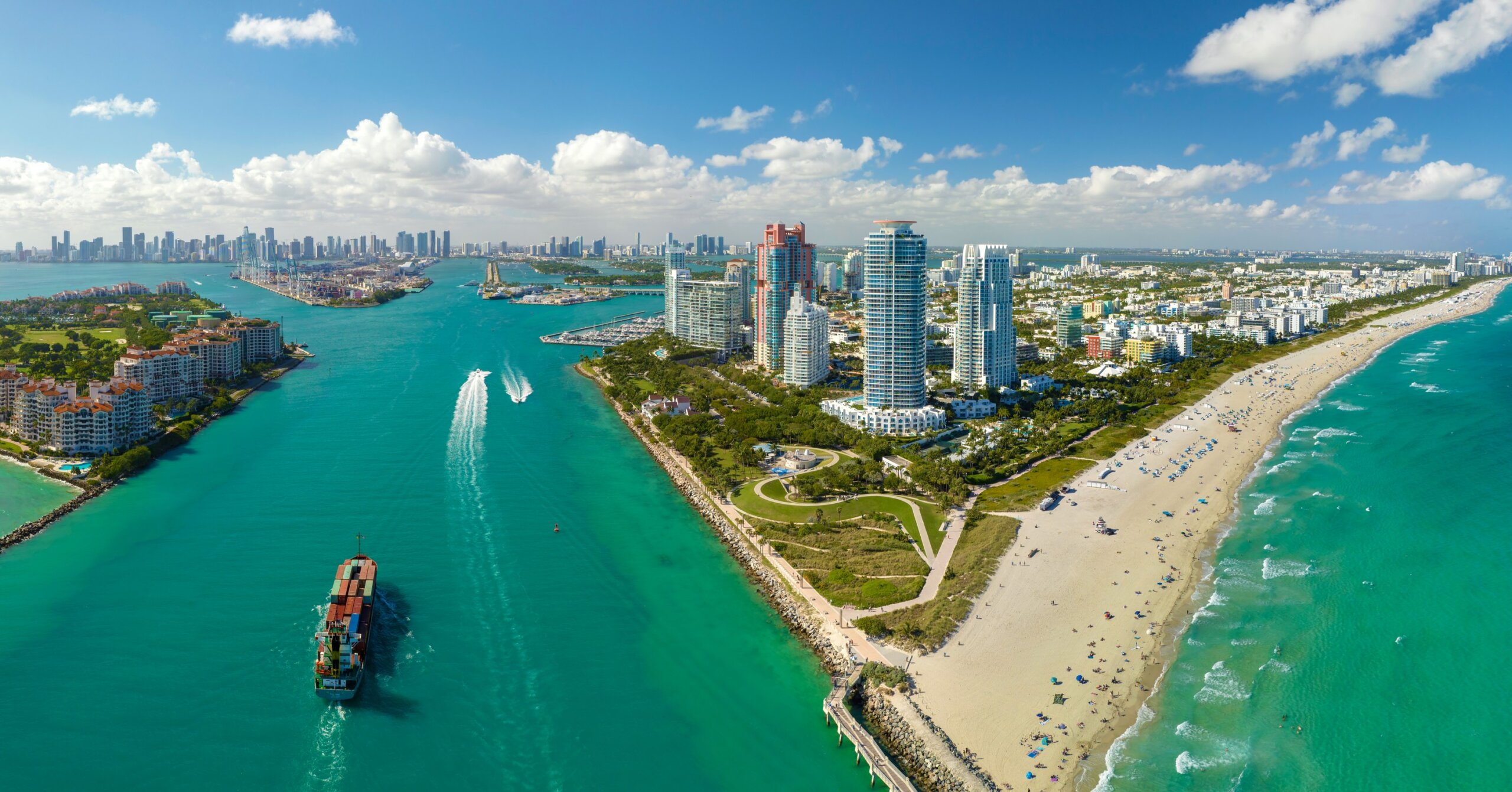 View from above of big container ship entering main channel in Miami harbor near South Beach high luxurious hotels and apartment buildings
