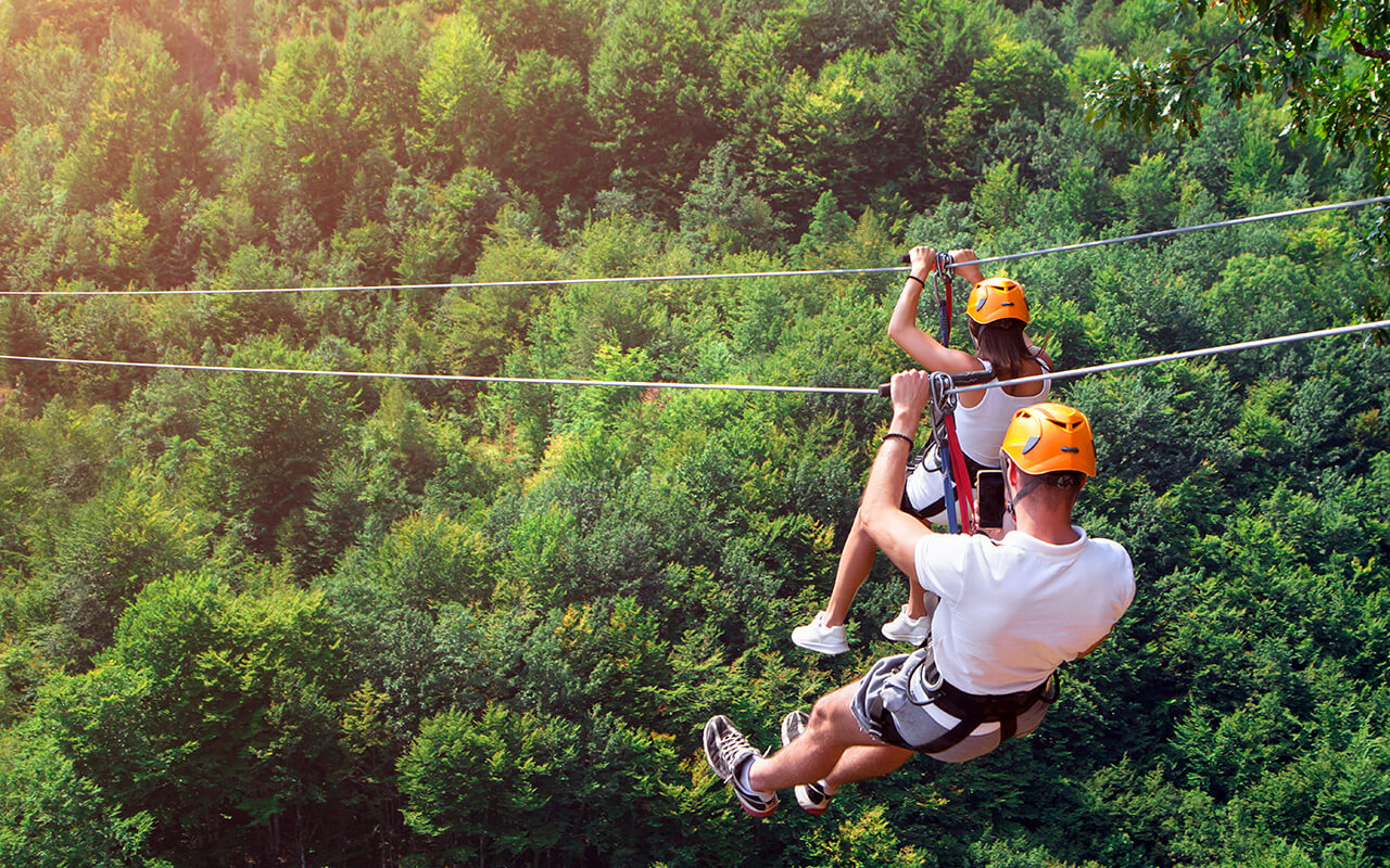 Zipline is an exciting adventure activity. Man and woman hanging on a rope-way. 