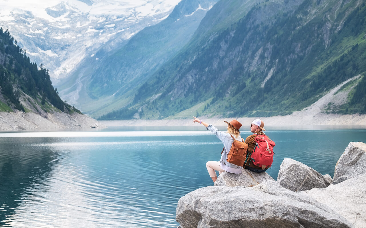Two people sitting on a rock overlooking a lake