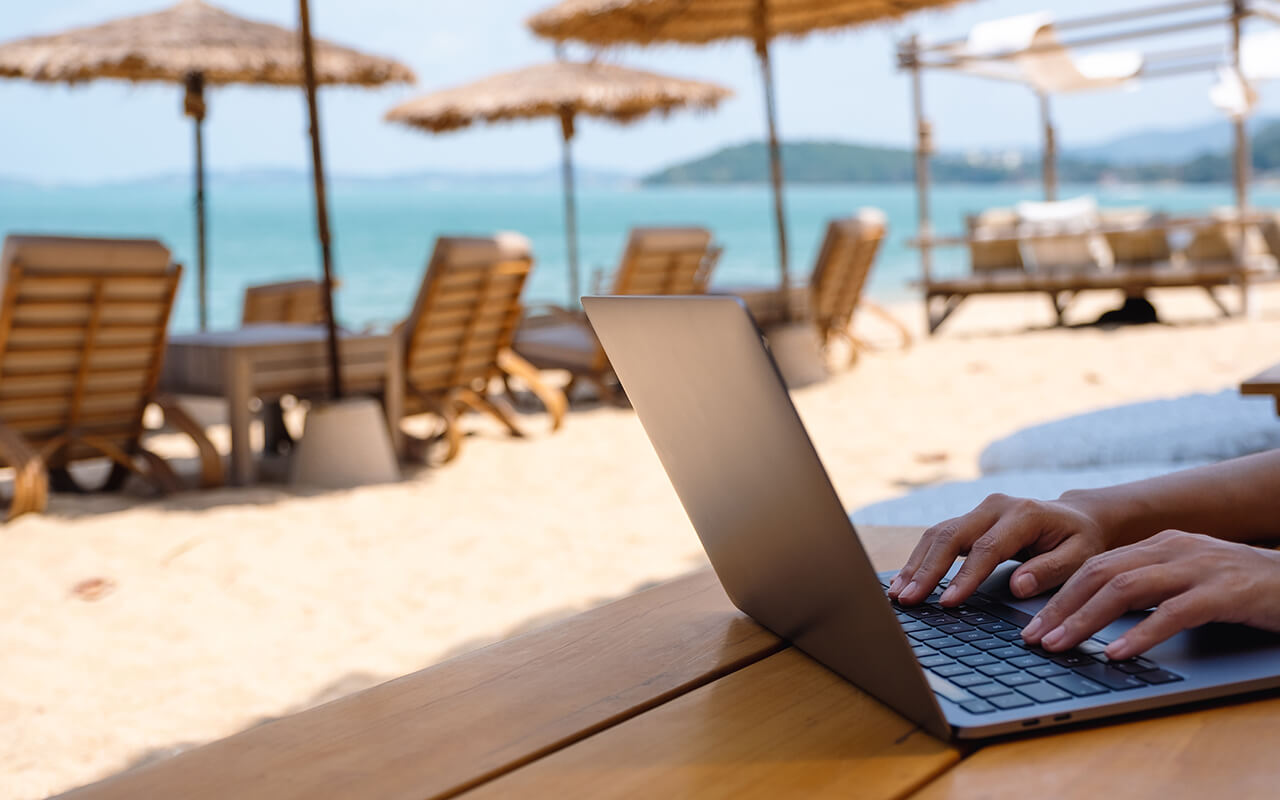 Closeup of a woman working and typing on laptop computer on the beach