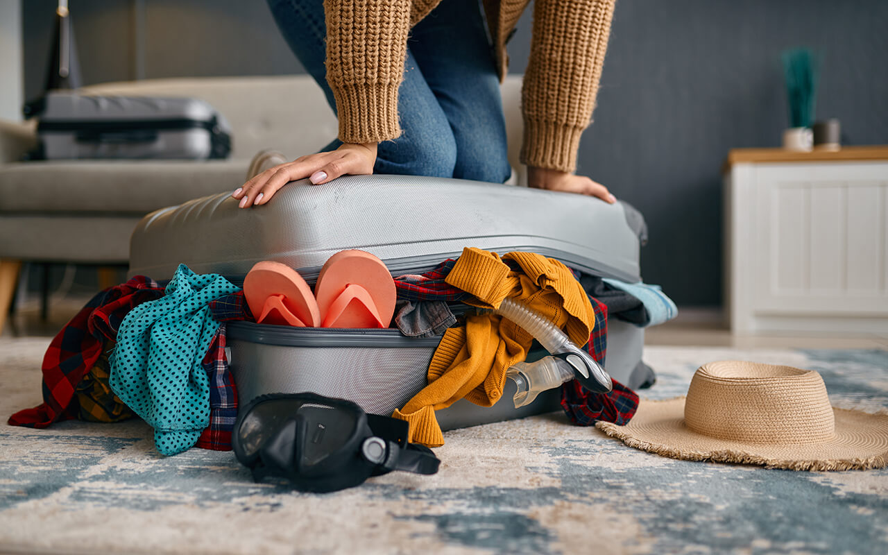 Woman sitting on luggage that is too full