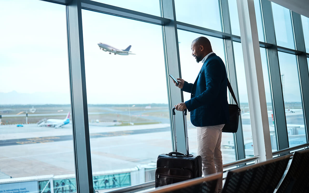 Black man with phone, airport window and plane taking off, checking flight schedule terminal for business trip.