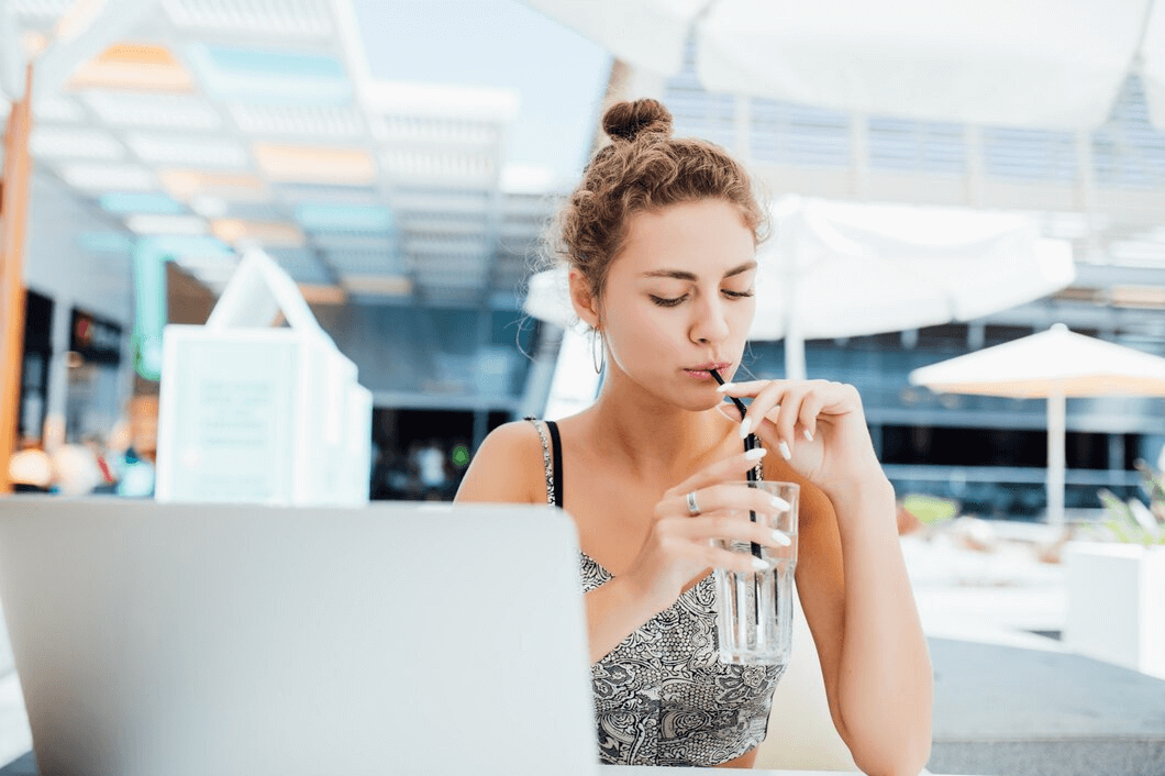Woman at airport drinking glass of water