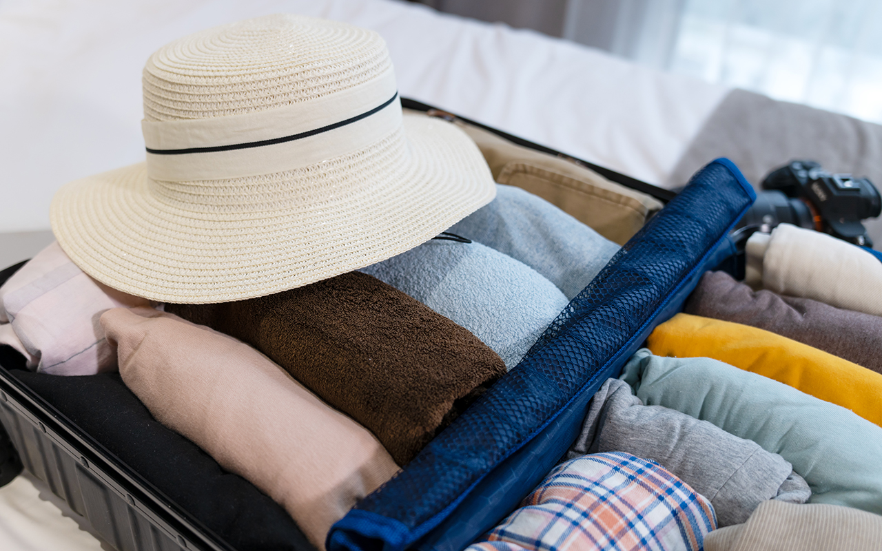 Packed suitcase with a hat on top