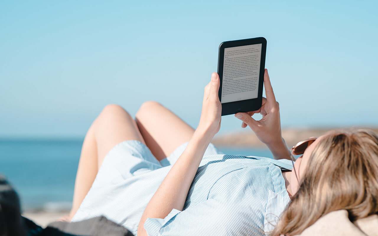 Woman reading kindle on beach