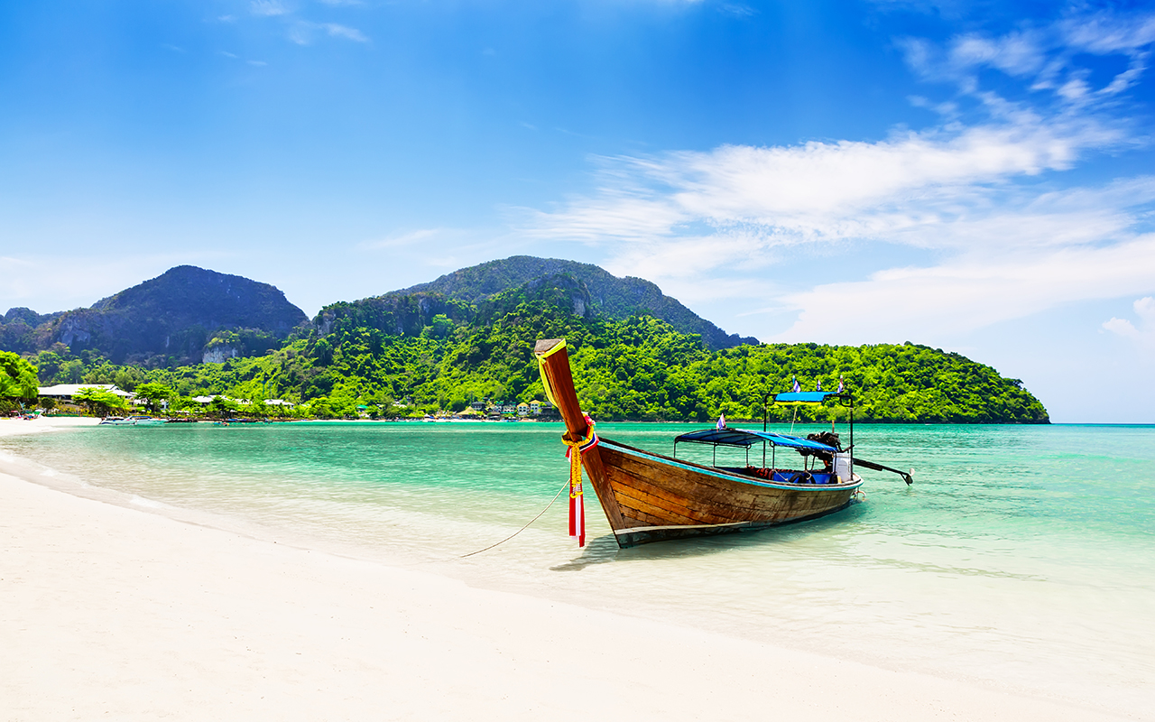 Thai traditional wooden longtail boat and beautiful sand beach.