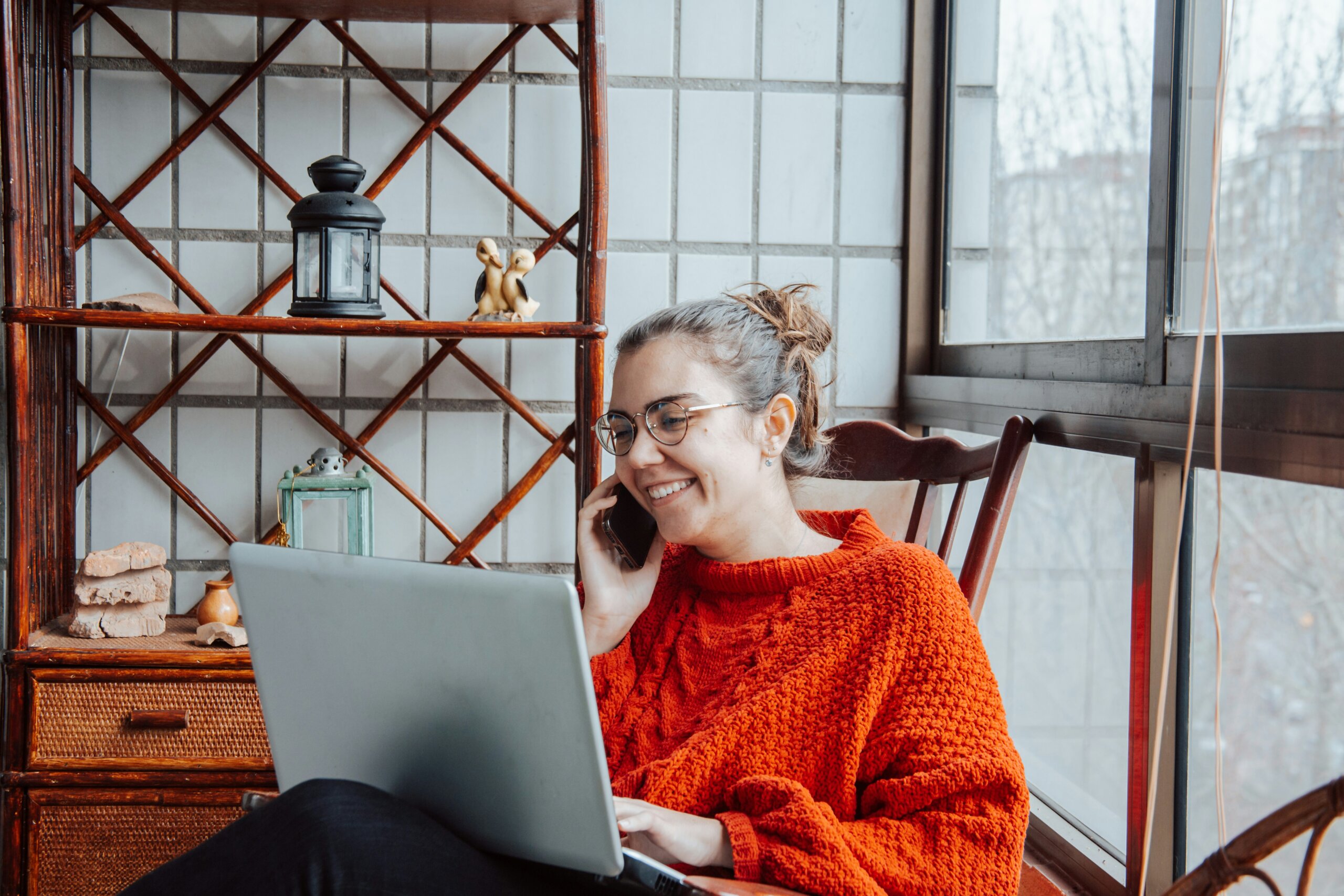 Woman talking on the phone and typing on a laptop