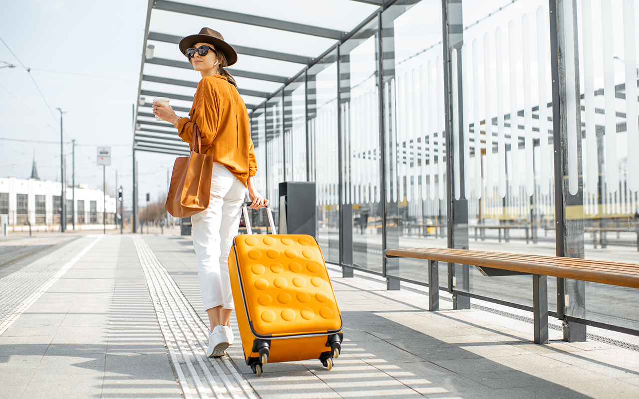 Young female traveler with a luggage at the transport stop
