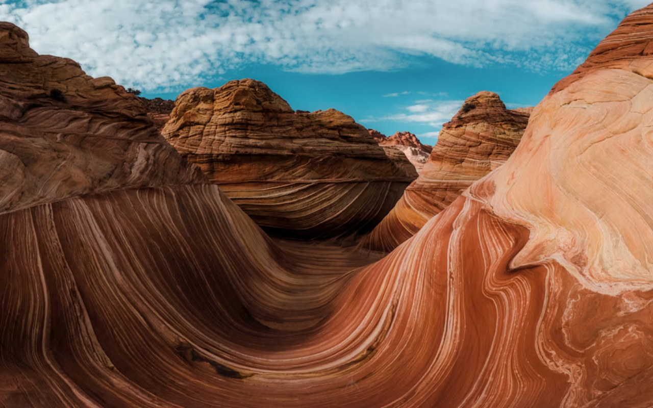Artistic, whimsical sandstone formations resemble waves in the red-tinted desert landscape.