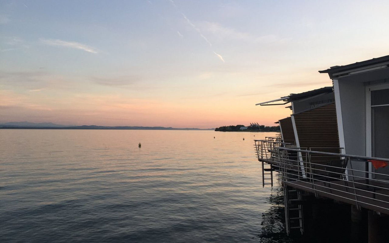 Modern stilted cabins at Hotel Palafitte extending over the clear waters of Lake Neuchâtel, Switzerland, with private wooden decks offering panoramic lake views.