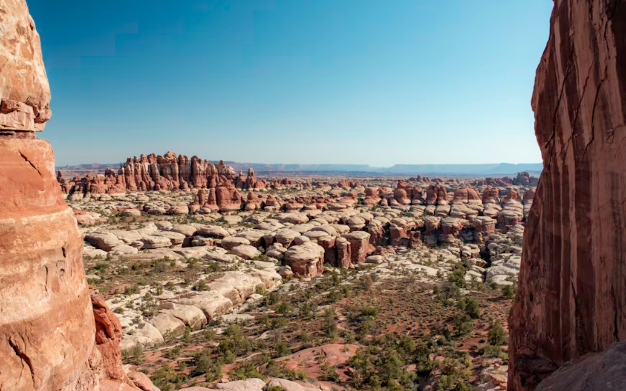 A red-soaked desert landscape with unique rock formations and steep mesas in the background.