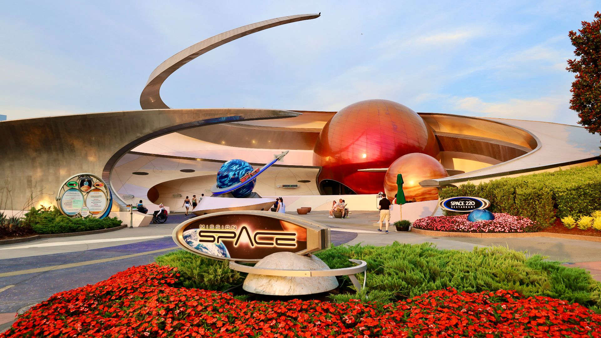 Disney’s Mission: SPACE – Orange Side, featuring a bold, metallic façade with a giant spinning Earth sculpture and sleek mission insignia. The dramatic architecture and deep space theming hint at the intense astronaut training experience that awaits inside.