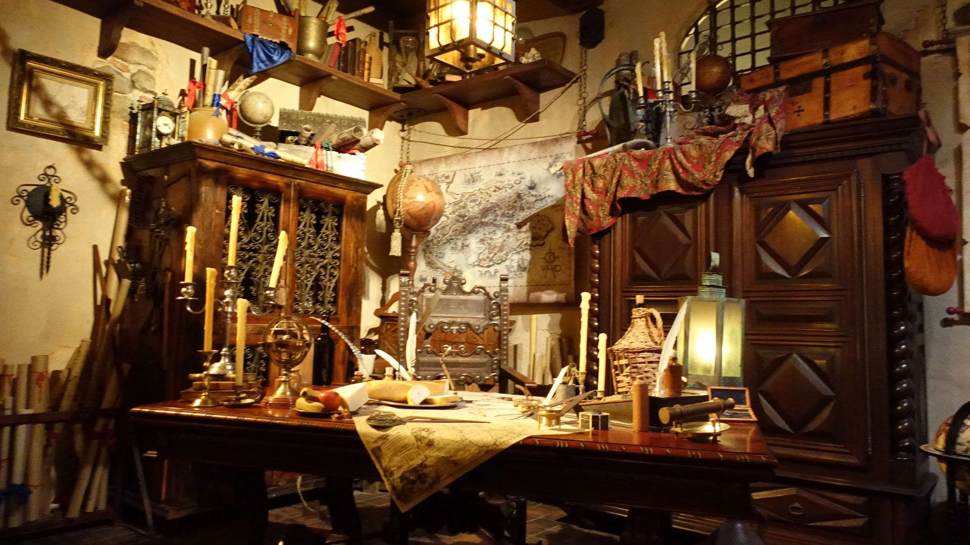 Disney’s Pirates of the Caribbean ride, featuring a weathered wooden desk cluttered with nautical maps, candles, and antique treasures.