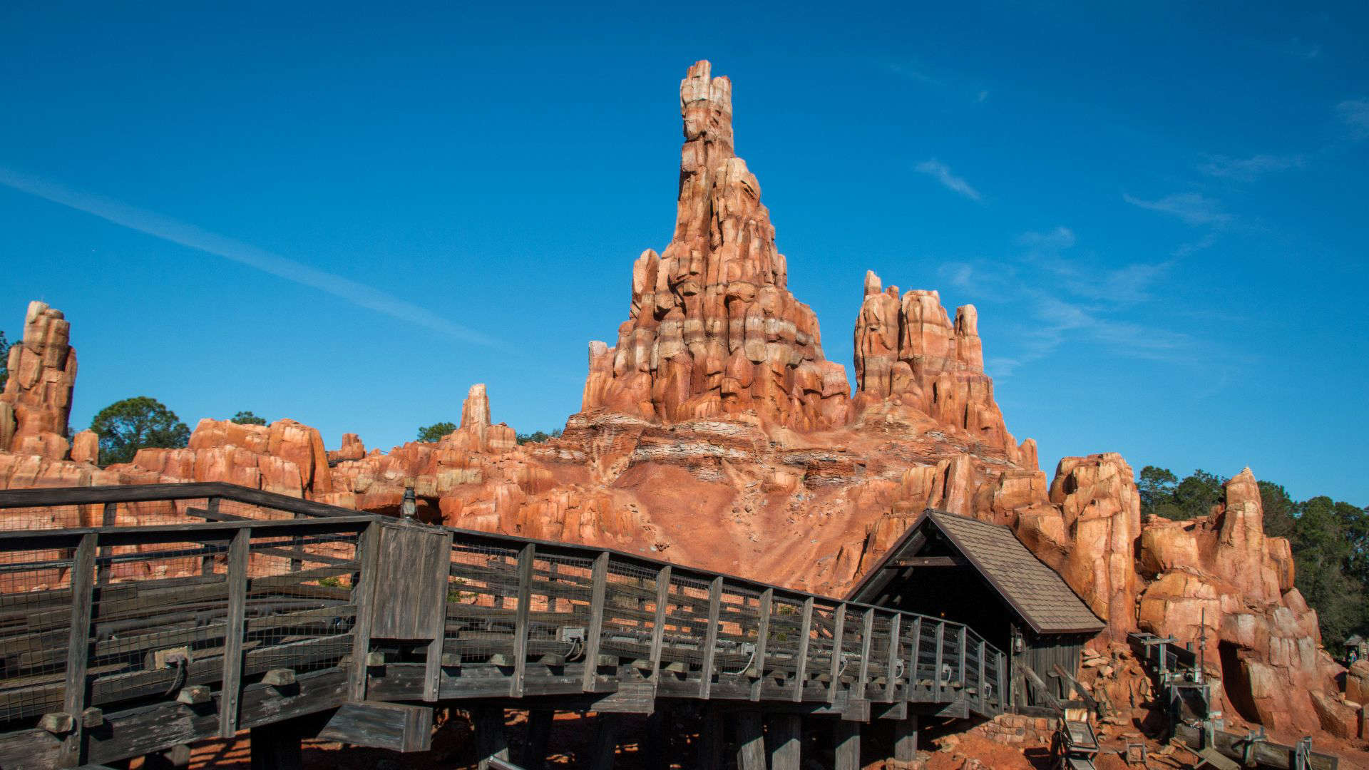 Rugged red rock formations and wooden mine structures of Disney’s Big Thunder Mountain Railroad, set against a desert canyon backdrop. The runaway train coaster winds through towering buttes and old Western mining scenery, capturing the spirit of a wild frontier adventure.