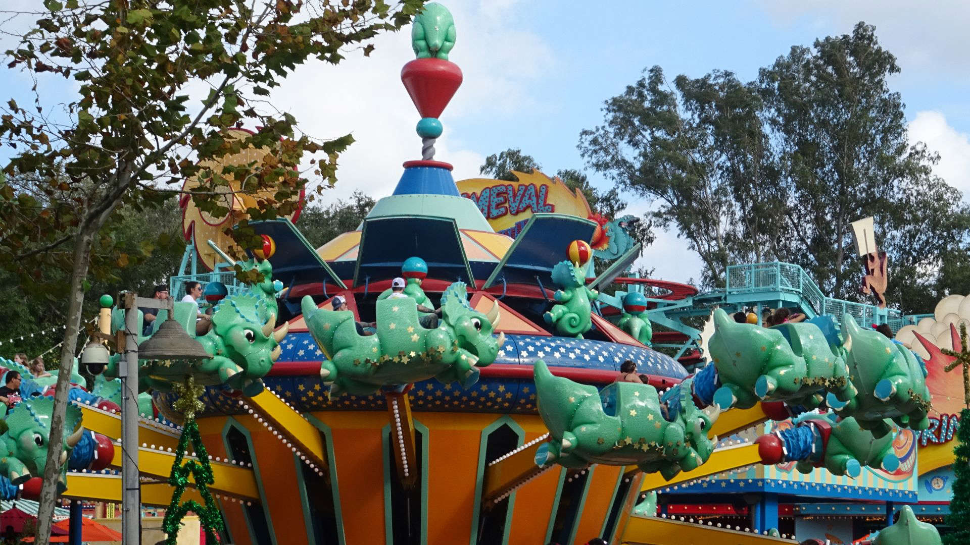 Guests riding cartoon-style triceratops on Disney’s TriceraTop Spin attraction.