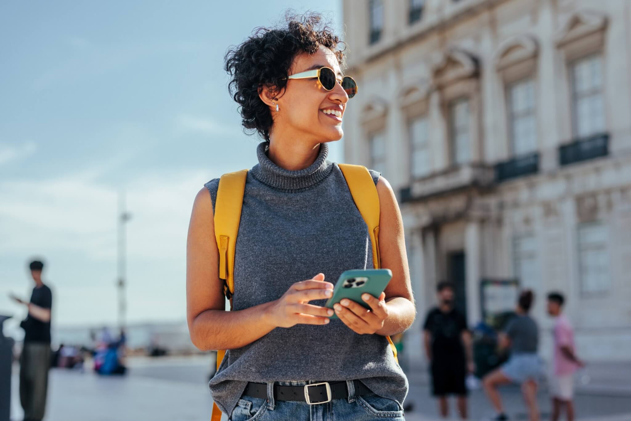 A solo female traveler confidently walking through a foreign city while checking directions on her phone
