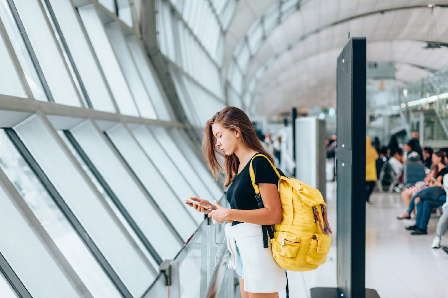 Teen girl waiting for international flight in airport departure terminal