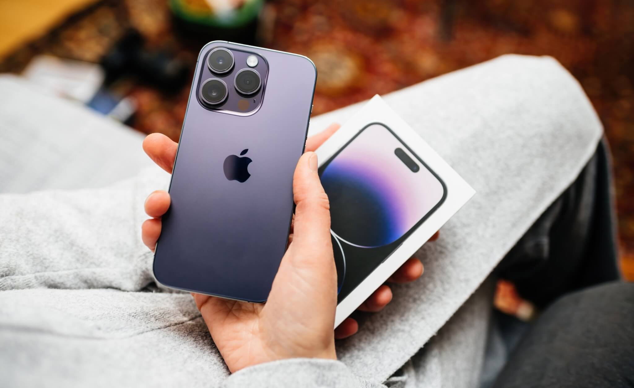 POV woman hand holding unboxing the package showing new Deep Purple Apple iPhone 14 Pro Max the sixteenth-generation flagship iPhones with no SIM card slot.