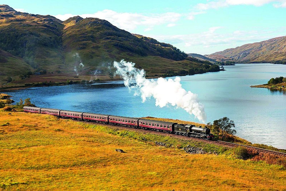 Jacobite Steam Train traveling through the Scottish Highlands beside a lake