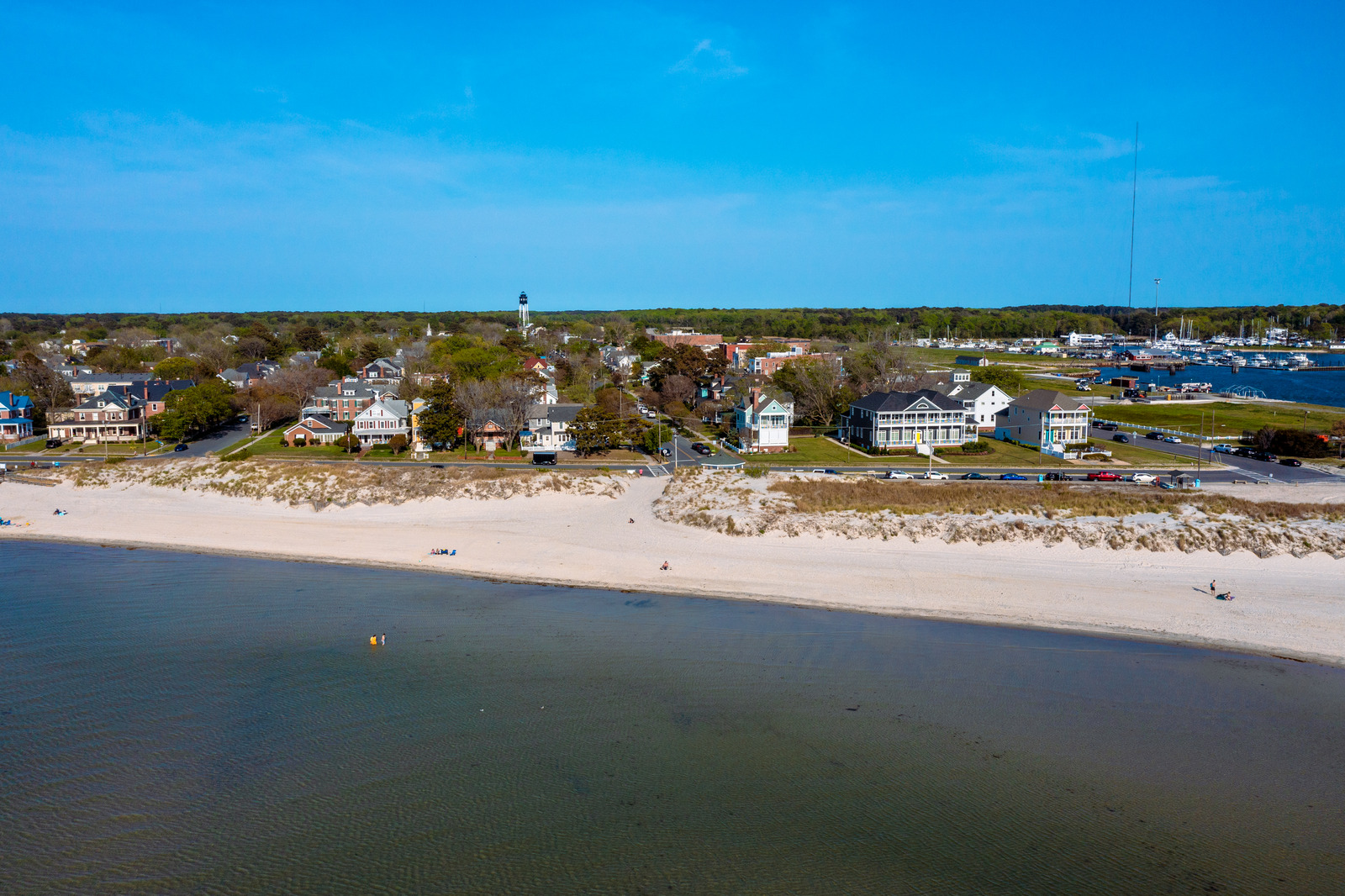 Serene coastline in Cape Charles, Virginia, with calm Chesapeake Bay waters, sandy beaches, and a quiet stretch of shoreline lined with colorful beach cottages.