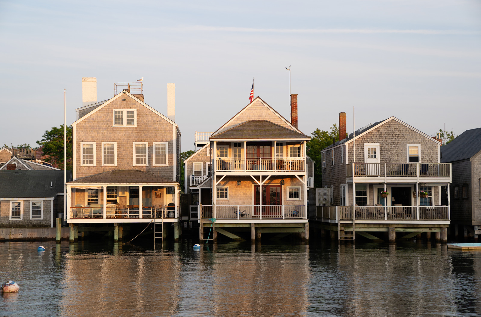 Classic gray-shingled cottages on stilts over the water in Nantucket, Massachusetts, with weathered docks and a serene harbor backdrop.