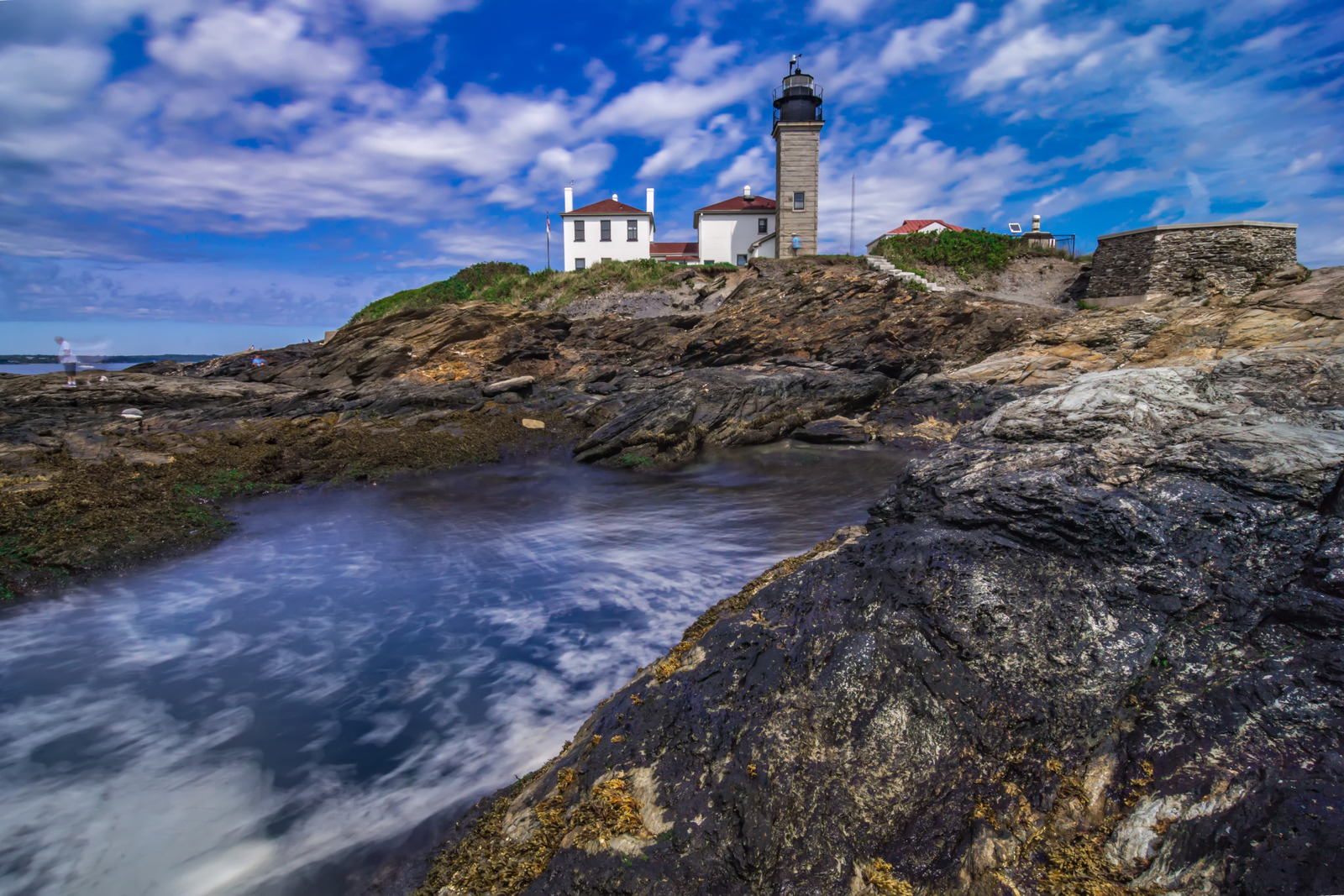 Historic lighthouse on the rocky coastline of Jamestown, Rhode Island, overlooking the Atlantic Ocean with waves crashing below and classic New England charm.