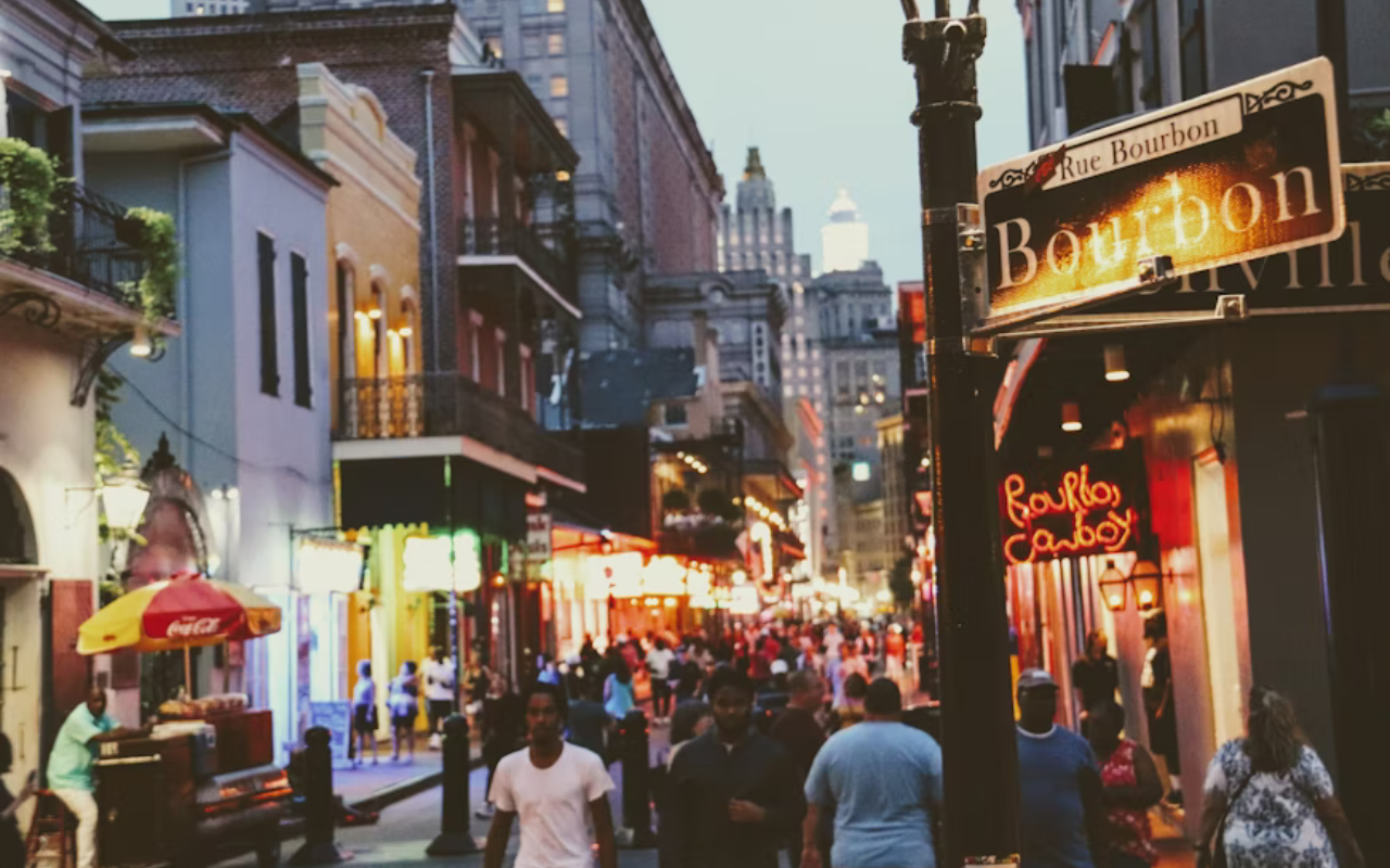 Colorful buildings and street musicians on Bourbon Street in New Orleans, celebrating Black culture, music, and resilience.