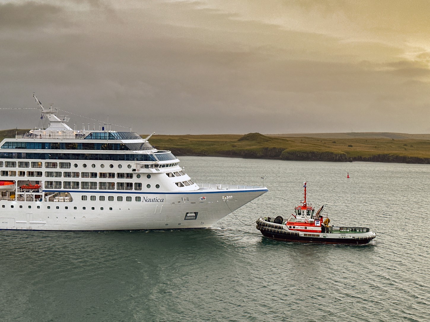 Oceania Cruises ship Nautica arriving in Reykjavík, Iceland with tugboat assistance at sunrise