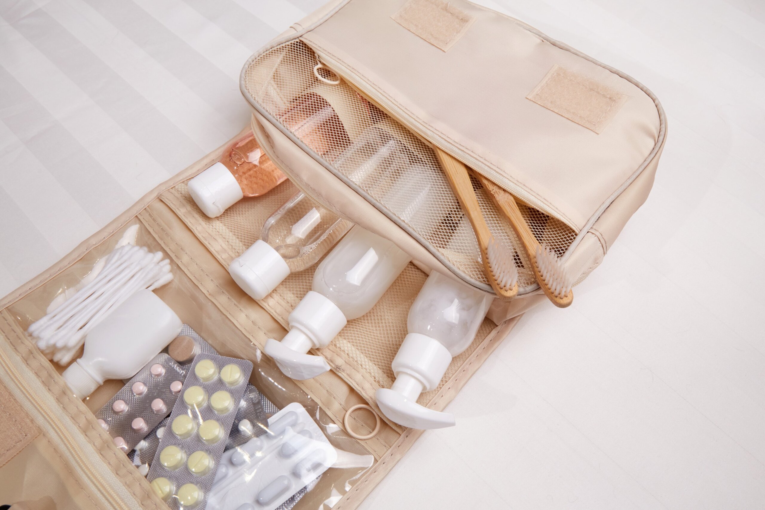 Travel set of toiletries on white bed linen.
