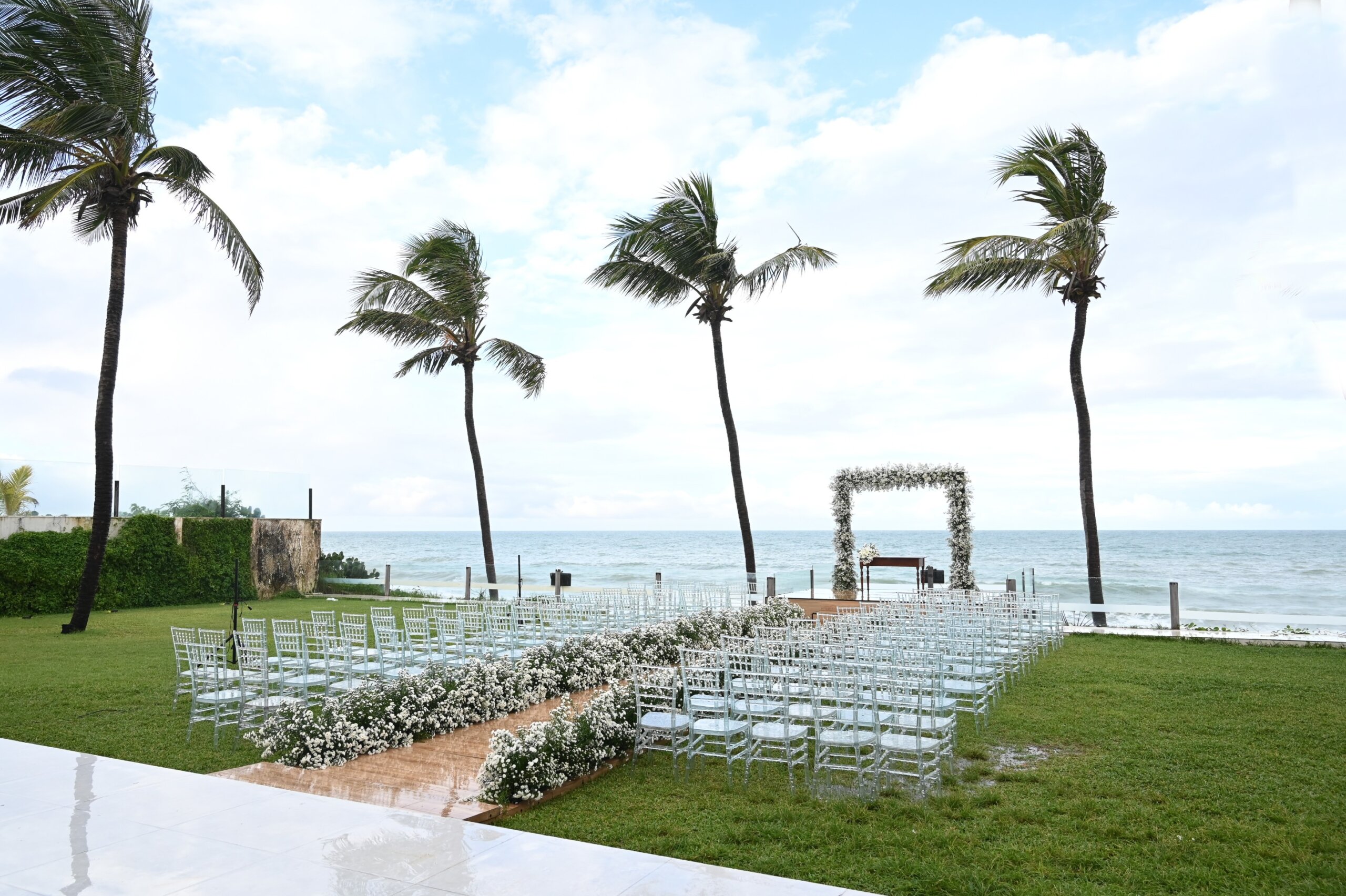 Beachfront wedding altar framed by palm trees with a central aisle leading to the ocean.

