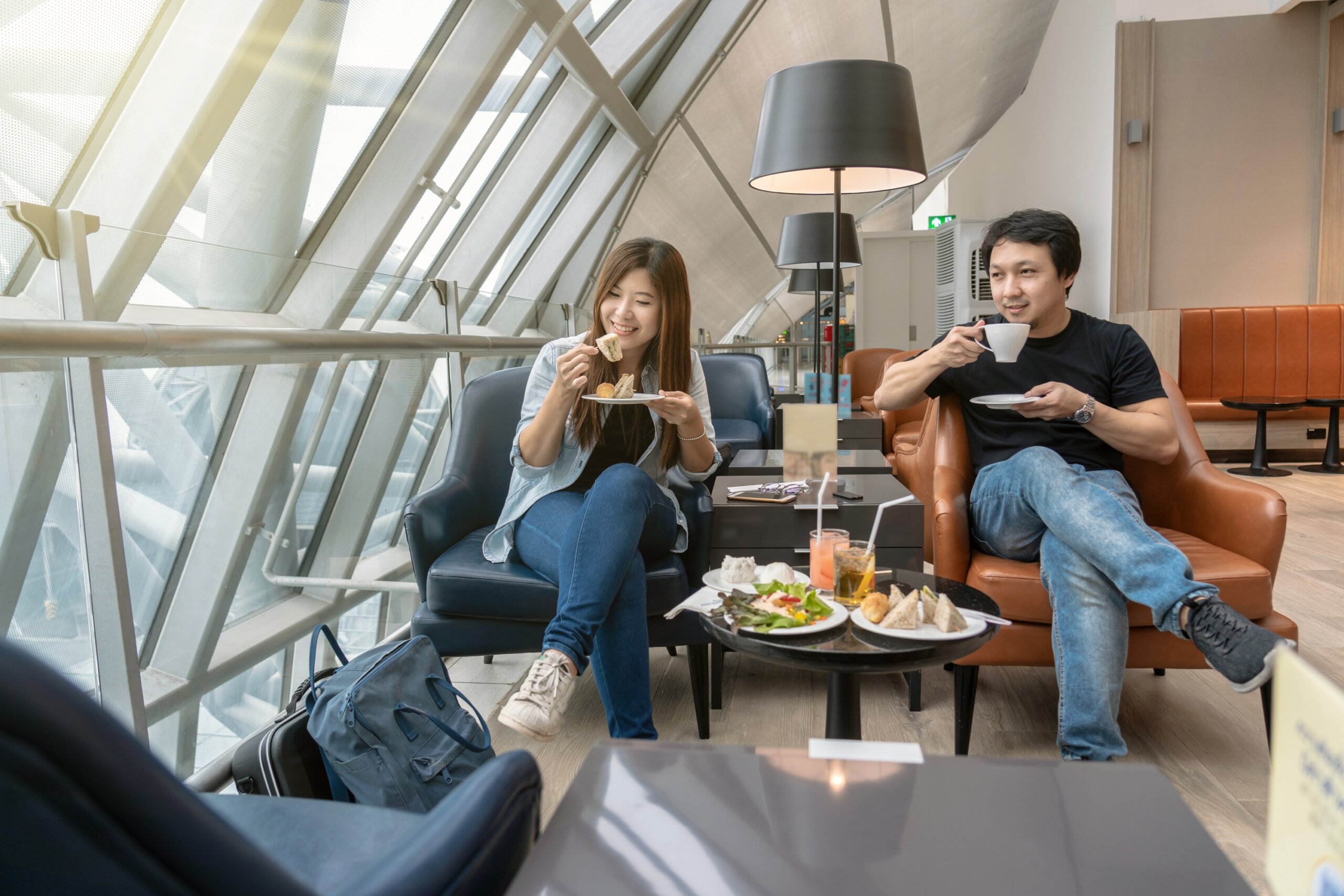 Asian couple sitting and eatting inn airport lounge when waiting the flight at modern international airport, travel and transportation concept