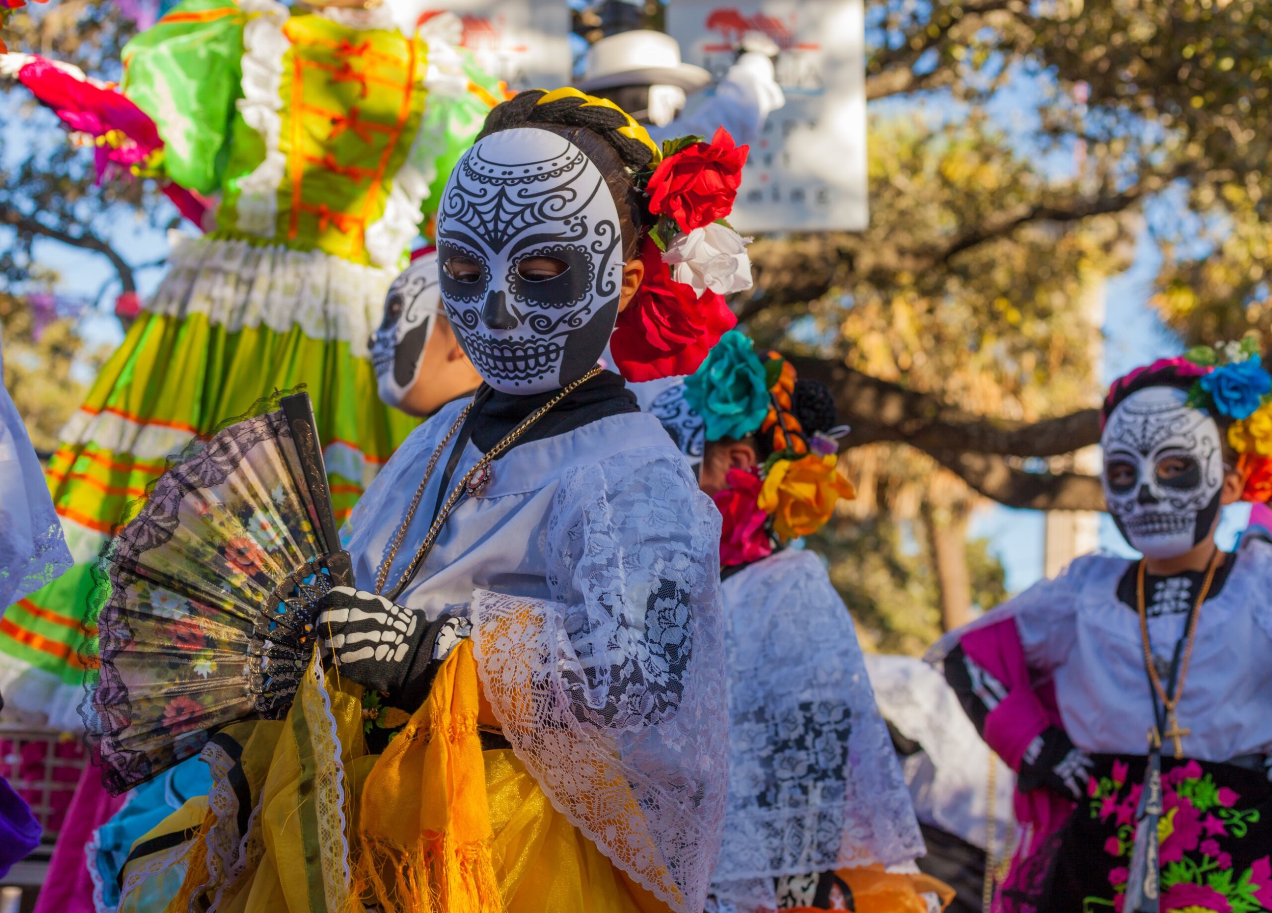 Group of unrecognizable women wearing traditional sugar skull masks and costumes for Dia de los Muertos celebration