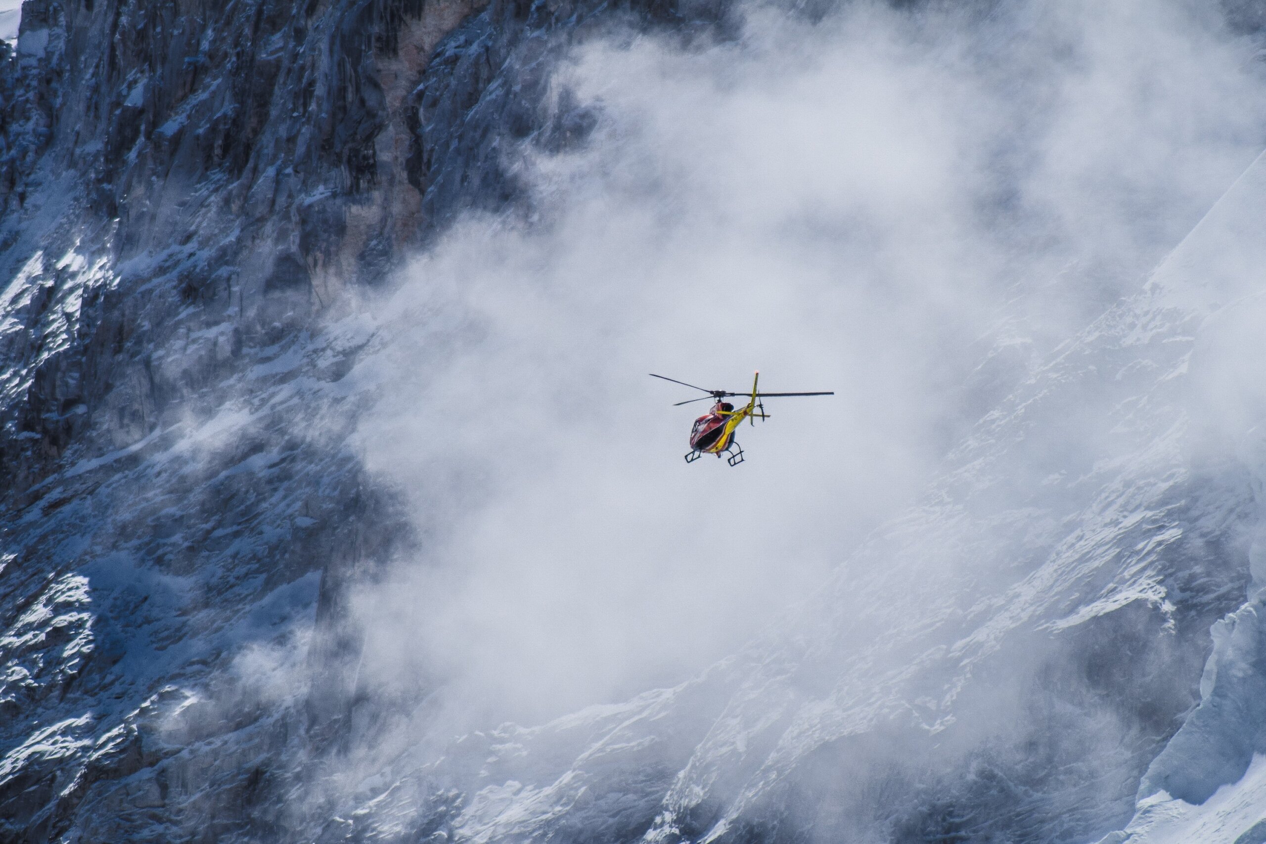 Helicopter flying toward Everest Base Camp through clouds over snow-covered Himalayan peaks