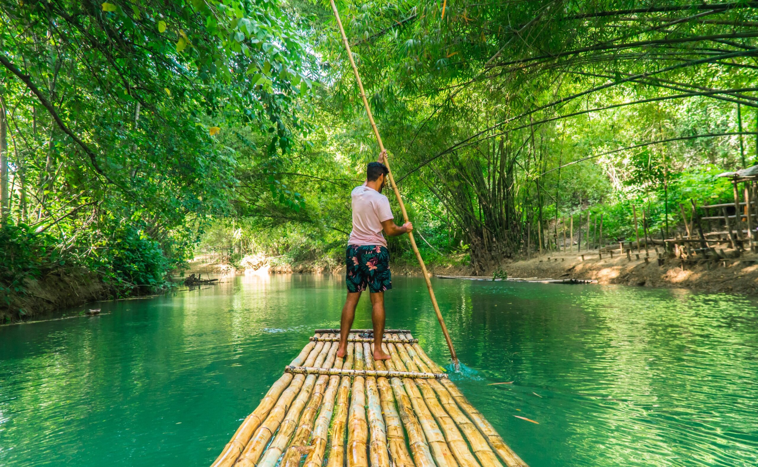Man rowing bamboo raft, Martha Brae. Tourist boy whilst on cruise on vacation in Montego Bay, Jamaica, Caribbean.