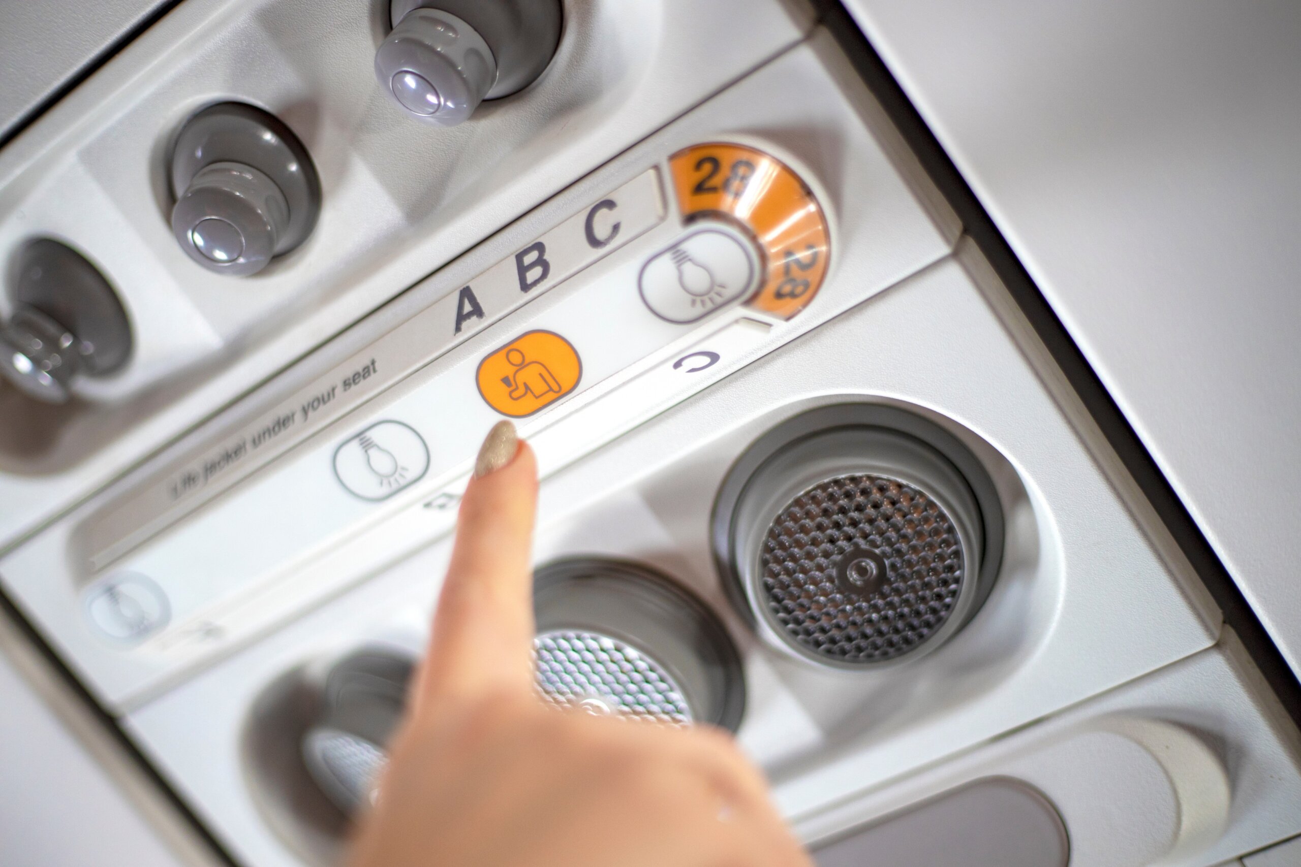 Female finger over flight attendant call button on airplane