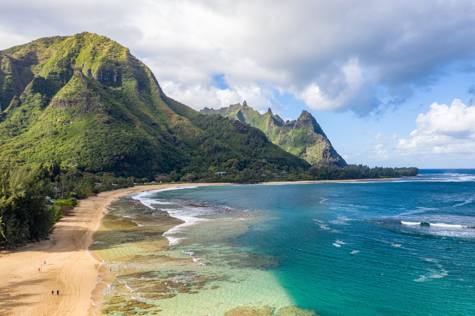 Aerial shot off the coast over Tunnels beach on Hawaiian island of Kauai with Na Pali mountains behind