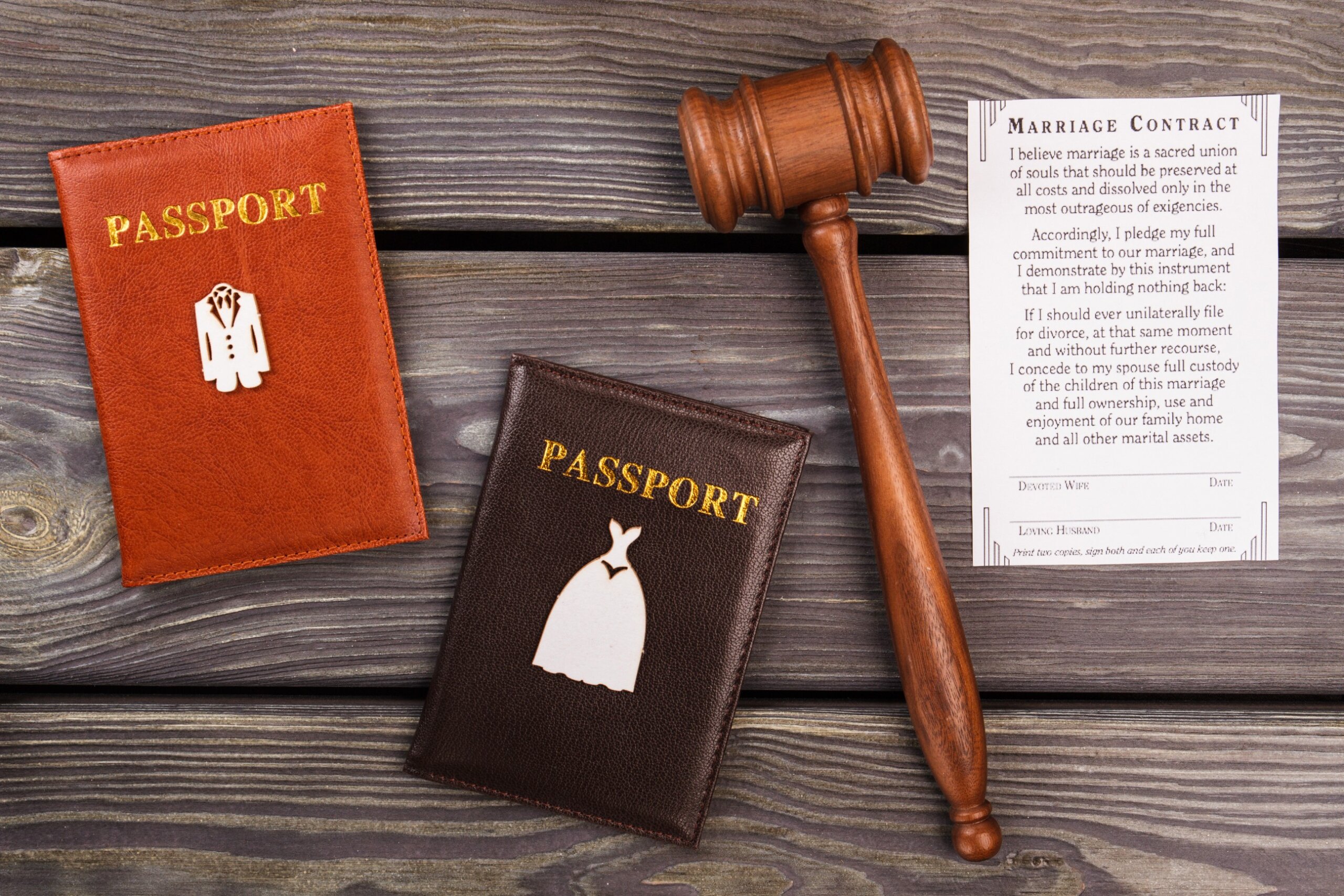 Flat lay of marriage contract paperwork with two passports and a judge’s gavel on a white table.