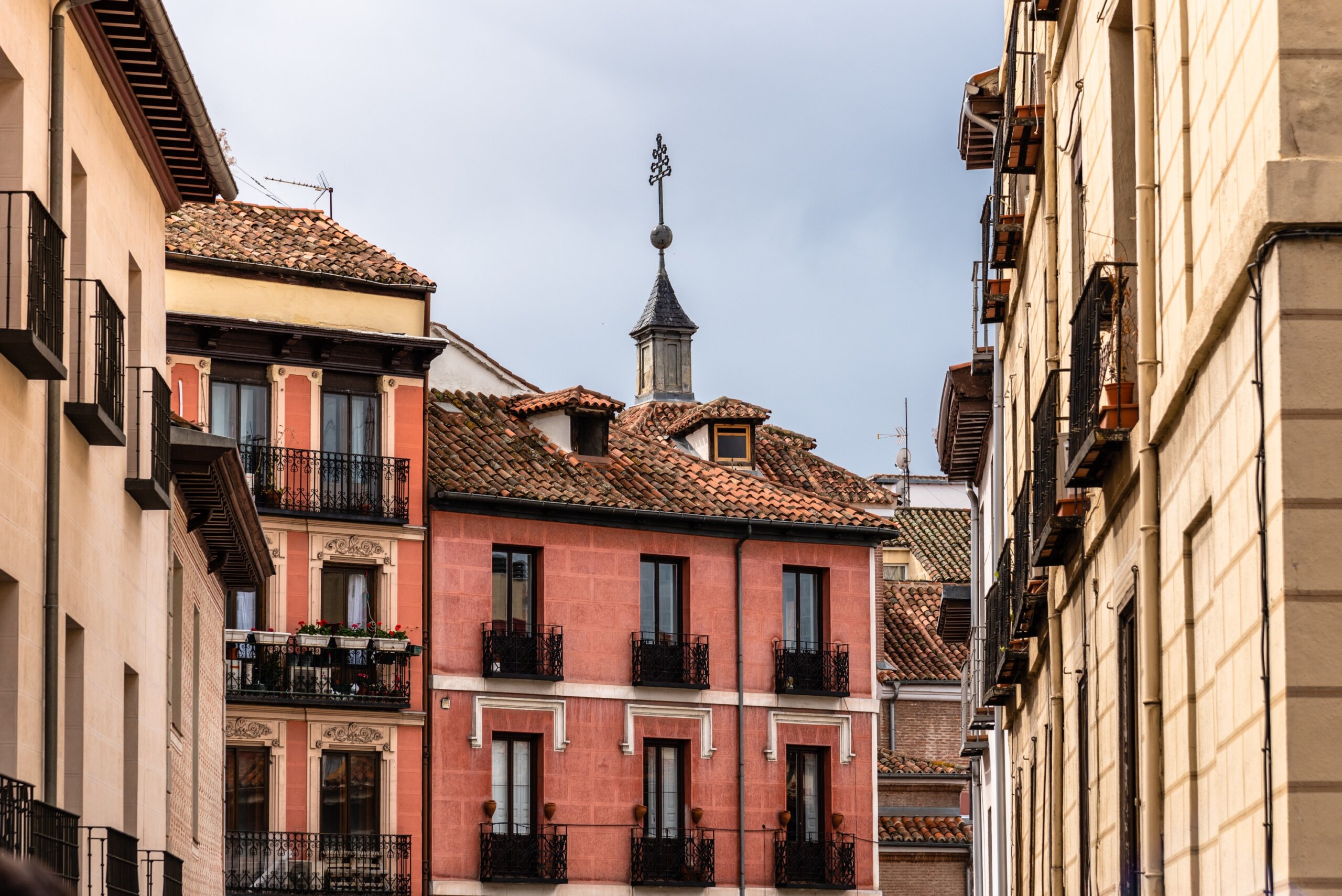 Colorful traditional residential buildings in central Madrid, Spain, showcasing historic architecture against a cloudy sky.