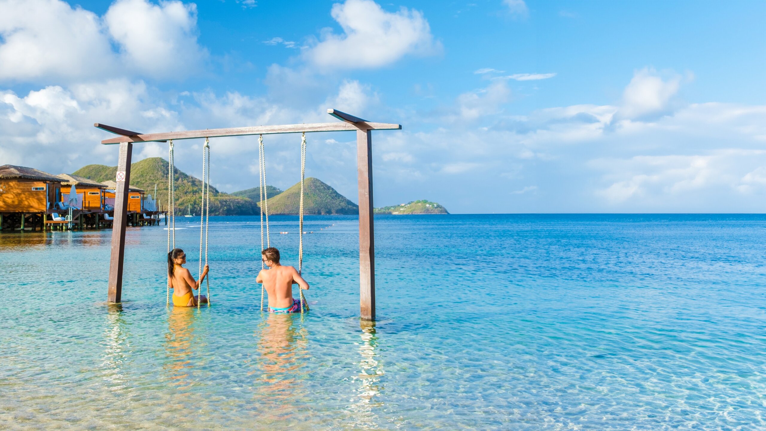 Couple on beach swing in St. Lucia Caribbean honeymoon – tropical island luxury vacation destination 2025