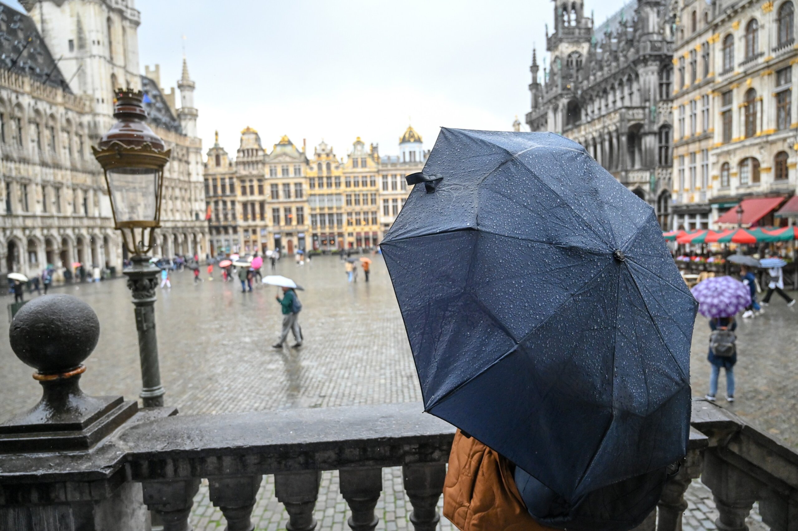 Woman holding umbrella during rain shower. People on the square in city center on rainy day.